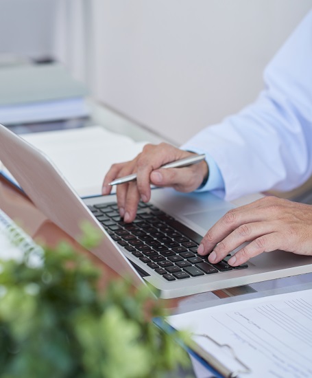Professional using a laptop beside paper records